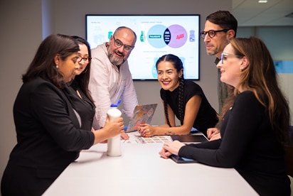 Seis funcionários da Colgate-Palmolive numa sala de reuniões a discutir um conceito de produto, com um diapositivo de apresentação num ecrã atrás deles.